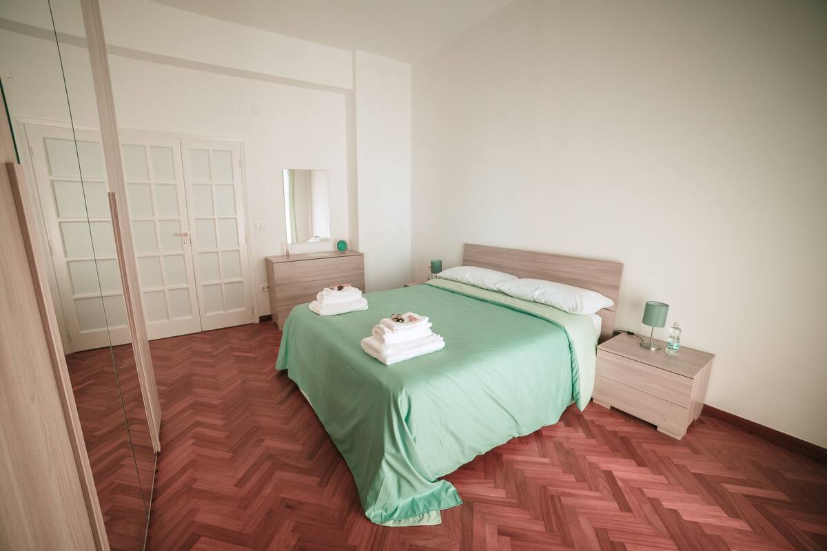 Ein Hotelzimmer mit Bett, Nachttisch, Spiegel und Kleiderschrank.
