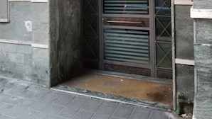 Entrada de un edificio con una reja metálica y un pequeño escalón de acceso.