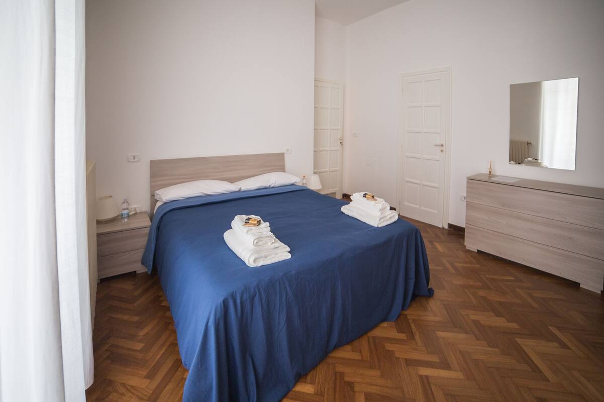 Ein Hotelzimmer mit Bett, Kommode, Spiegel und Tür.