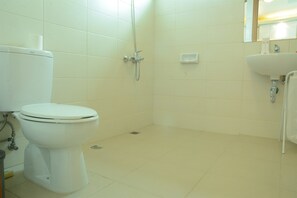 A bathroom with a toilet, a shower, and a sink.