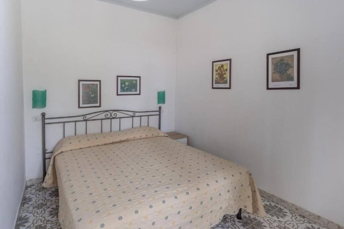 Een slaapkamer met een bed, twee ingelijste foto’s aan de muur en een kamerbreed tapijt.