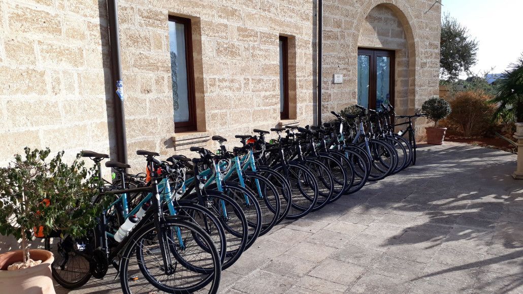 Uma fileira de bicicletas estacionadas em frente a um edifício de pedra com janelas em arco.