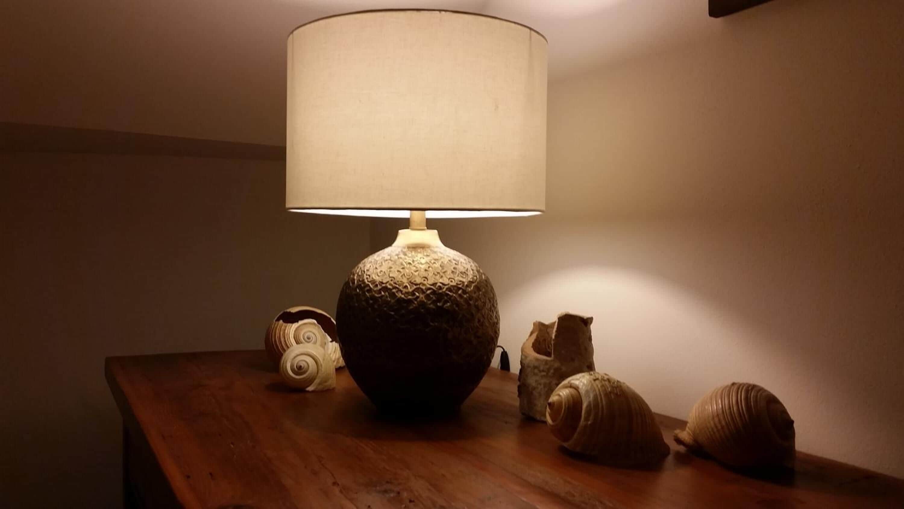 A wooden table with a textured lamp and decorative shells.