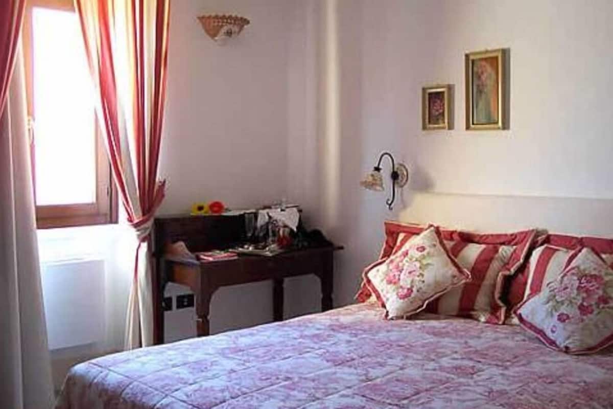 Una camera da letto con un letto, una scrivania e una finestra con tende.