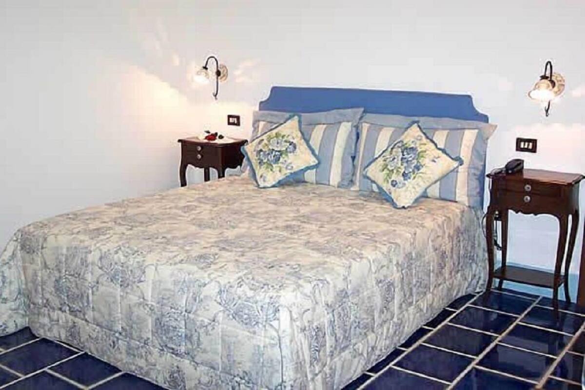 Una camera da letto con un letto grande, due comodini e lampade a parete.