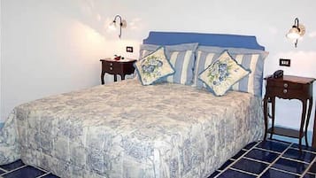 A bedroom with a large bed, two bedside tables, and wall-mounted lamps.