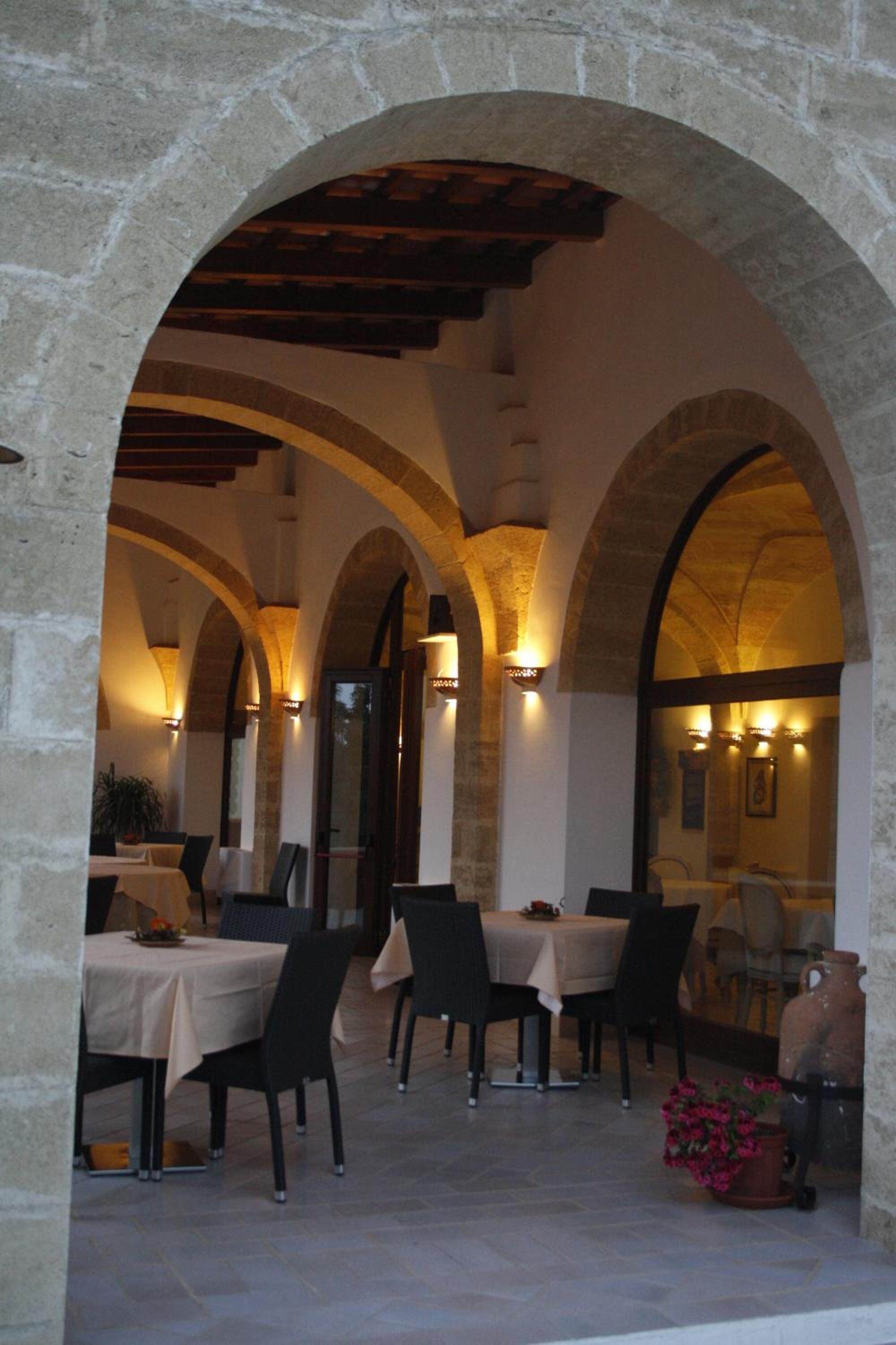 An outdoor dining area with stone arches, tables, and chairs.
