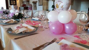 Ein Tisch festlich gedeckt, mit einem pink-weißen Farbkonzept, inklusive Luftballons und herzförmigen Servietten.