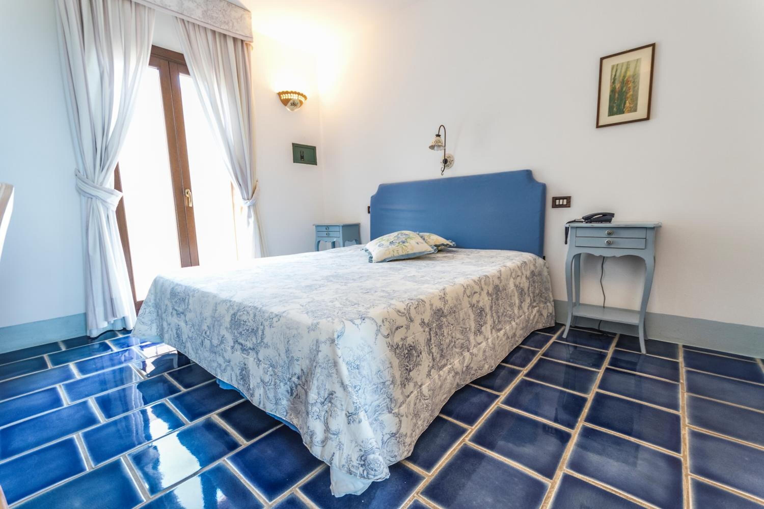 Une chambre à coucher avec un lit, une table de chevet, une lampe et une porte.