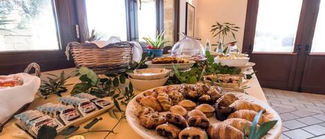 Uma mesa de buffet com diversos pastéis, incluindo croissants e pastéis recheados, além de vários potes de Nutella.