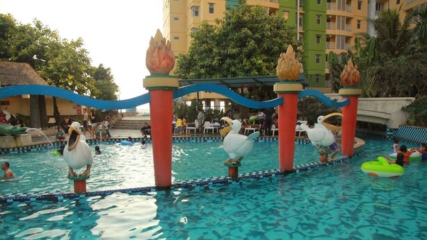 A swimming pool with decorative flamingo statues and a blue border. - Simply Studio Room at Grand Serpong Apartment By Travelio (Tangerang)