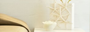 A white vase with a geometric design on a white table next to a beige sofa. - Hotel Aquarius (Cattolica)
