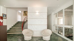 A modern interior with a marble staircase, two plush armchairs, and a glass door leading to a dining area. - Hotel Aquarius (Cattolica)