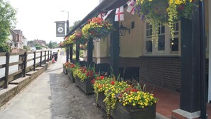 A pub with outdoor seating, flower boxes, and a signboard. - The Flying Bull Inn (Liss)