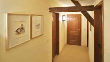 A hallway with wooden doors, framed artwork on the walls, and a carpeted floor.