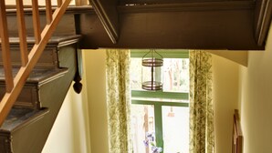 Een houten trap met een leuning, leidend naar een kamer met een raam en een bloempot.
