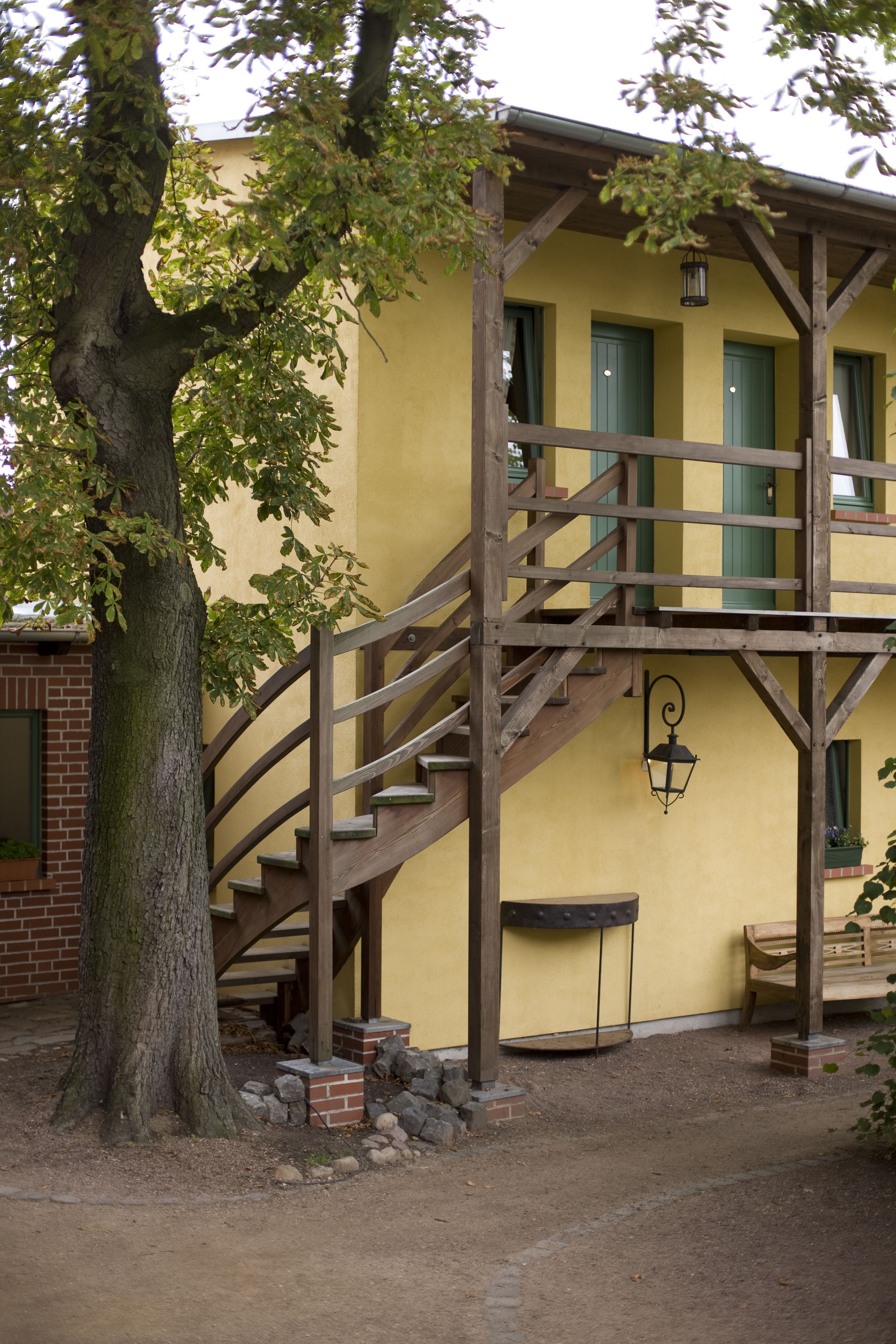 A yellow building with a wooden staircase leading to a balcony.