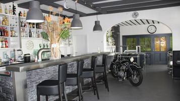 A bar area with a stone counter, black bar stools, and a motorcycle in the background.