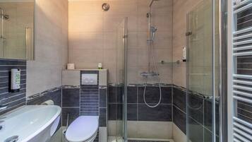 Un baño moderno con ducha acristalada, inodoro blanco y bañera.