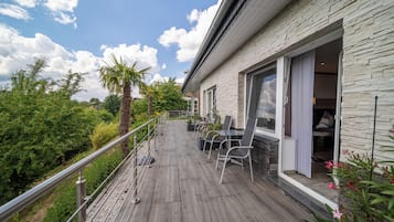 A modern outdoor patio with a stone wall, a wooden deck, and a seating area with chairs and a table.