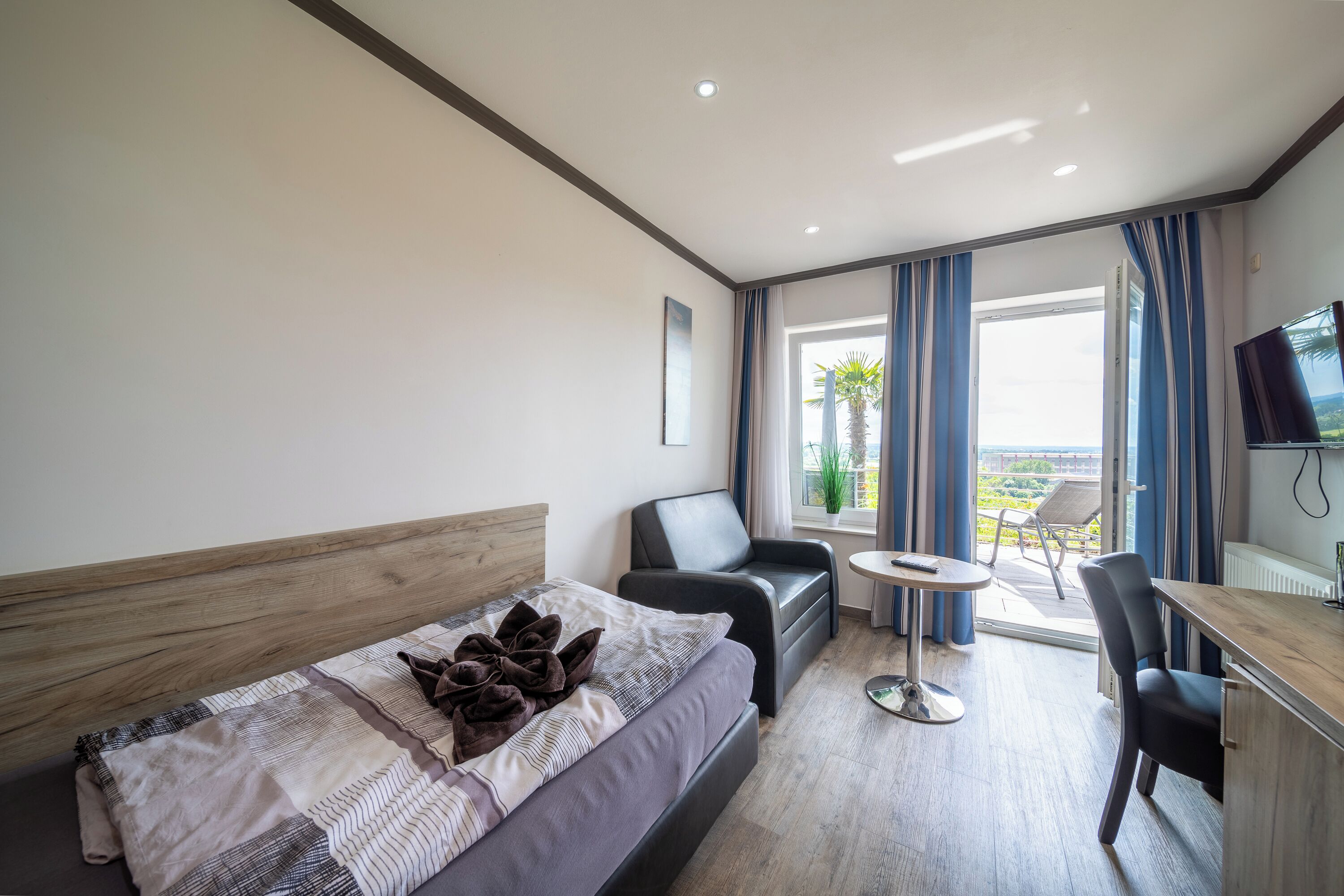 Una habitación de hotel moderna con cama, escritorio, silla y televisor.