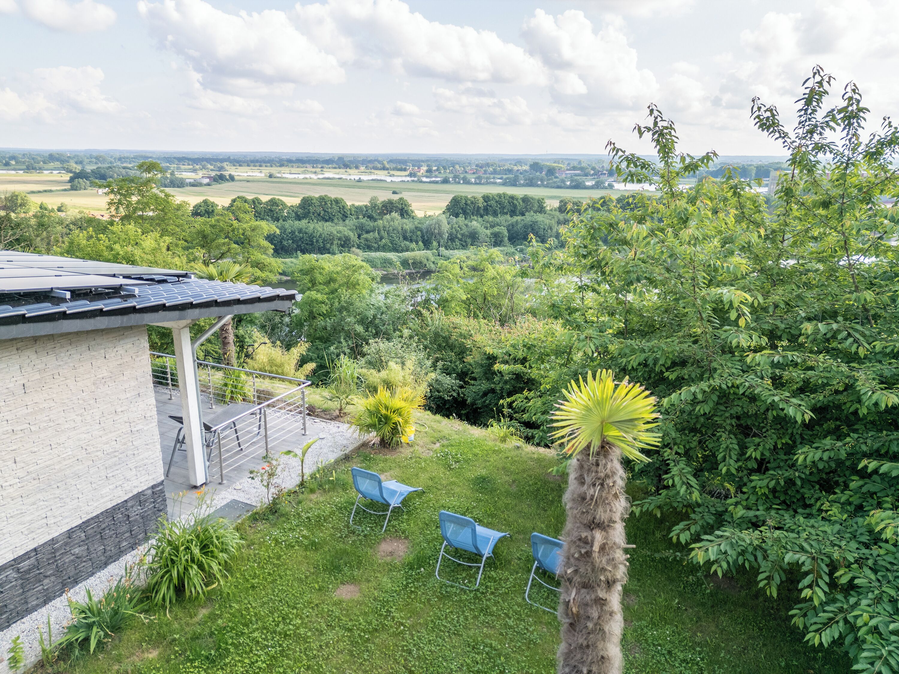 Una casa con patio, vistas al campo y un árbol en primer plano.