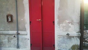 A red door with a brass handle, a small wall-mounted light, and a number '1' on the wall. - B&B Brunate Kangucavallo (Brunate)