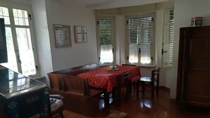 A dining area with a wooden table and chairs, a sofa, and a jukebox. - B&B Brunate Kangucavallo (Brunate)