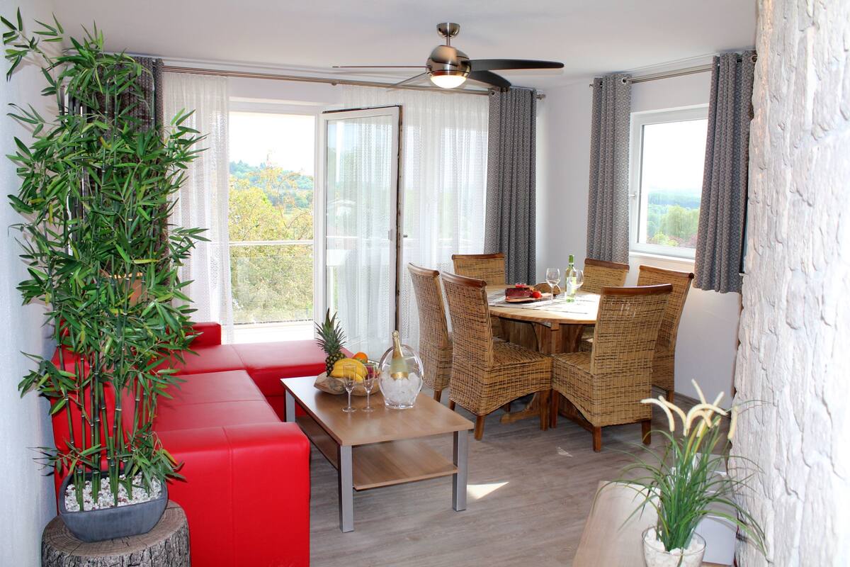 A dining area with a table, chairs, and a potted plant.
