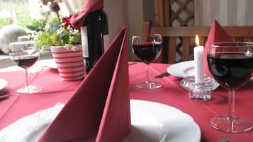 A table set with red napkins, wine glasses, a candle, and a bottle of wine.
