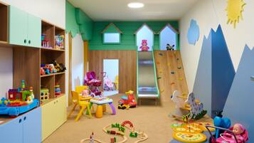 A children's playroom with a slide, climbing wall, and various toys.