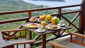 A wooden deck with a table set for breakfast overlooking a scenic lake and hills.