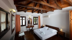 A bedroom with a wooden ceiling, a large bed, a desk, and a chair.