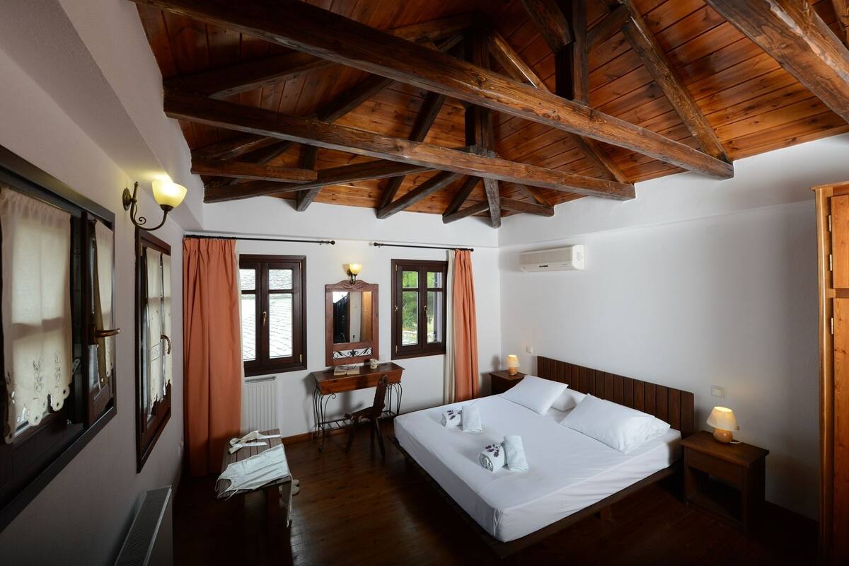 Une chambre avec un plafond en bois, un grand lit, un bureau et une chaise.