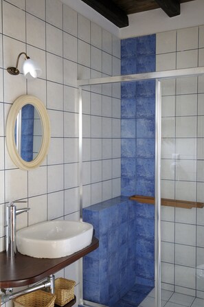 A bathroom with a white sink, a mirror, and a shower with blue tiles.