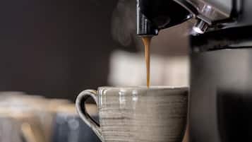 Una máquina de café vertiendo café en una taza de cerámica.