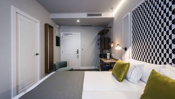 Habitación de hotel moderna con cama, escritorio y silla. Se ve una puerta y una ventana.