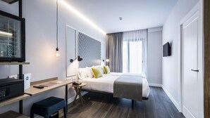 Et moderne hotelværelse med seng, skrivebord og TV.