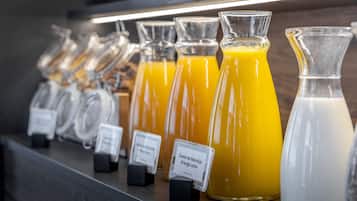 Varias botellas de jugo de naranja sobre una estantería, con etiquetas que indican los diferentes tipos.