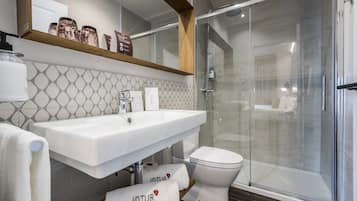 Un baño moderno con ducha de vidrio, lavamanos blanco y un inodoro.
