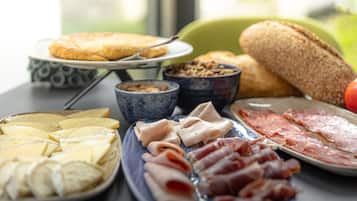 Une variété de fromages, de charcuteries et de pains sont disposés sur une table.