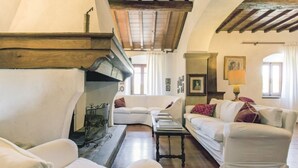 Una sala de estar acogedora con chimenea, sofás blancos y vigas de madera en el techo.