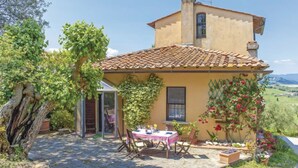 Una villa rústica con tejado de baldosas, un patio de piedra y un comedor con una mesa preparada para dos.