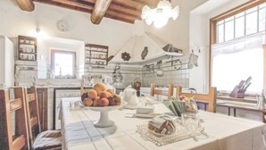 Una cocina con una mesa de comedor preparada para el desayuno, con frutas, pasteles y té.