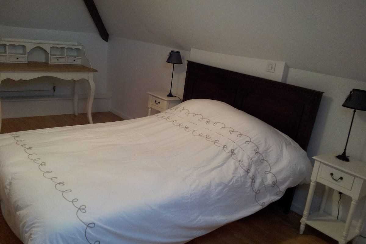 A bedroom with a bed, two bedside tables, a nightstand, a desk, and a lamp.