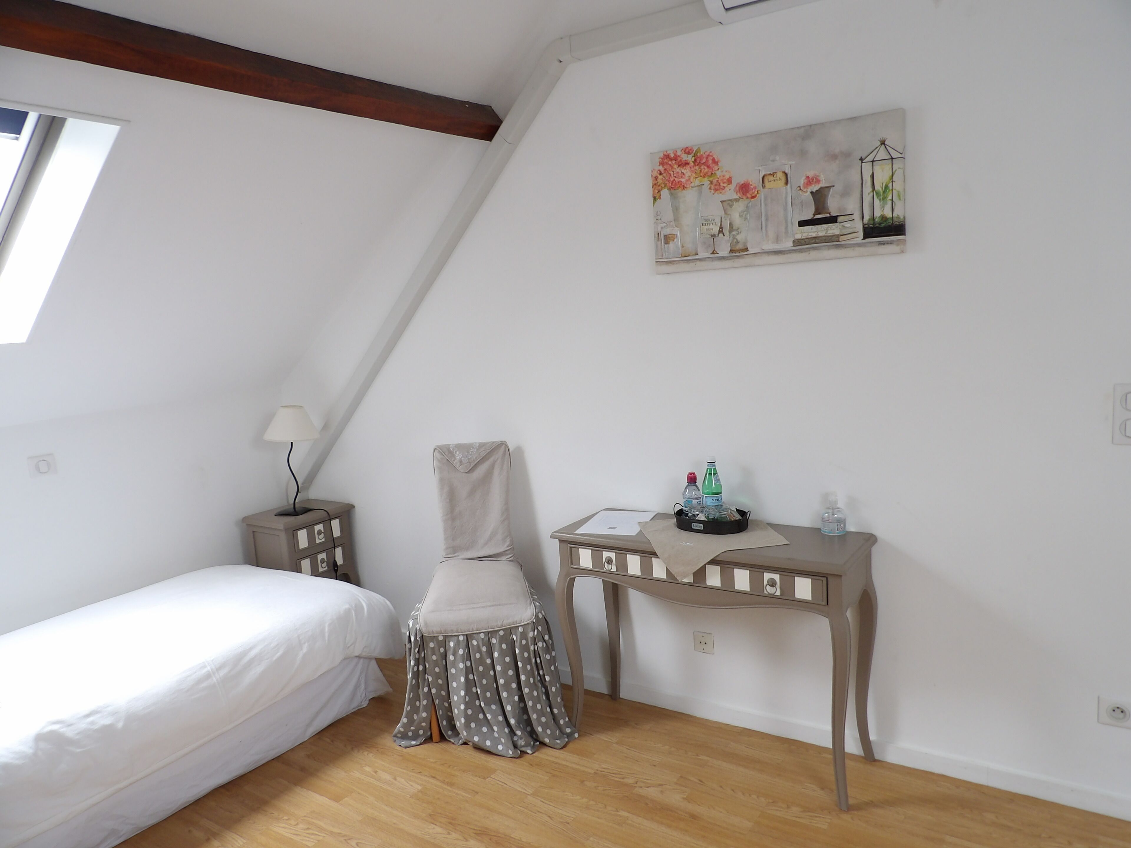 A bedroom with a bed, a chair, a desk, and a painting on the wall.