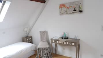 A bedroom with a bed, a chair, a desk, and a painting on the wall.