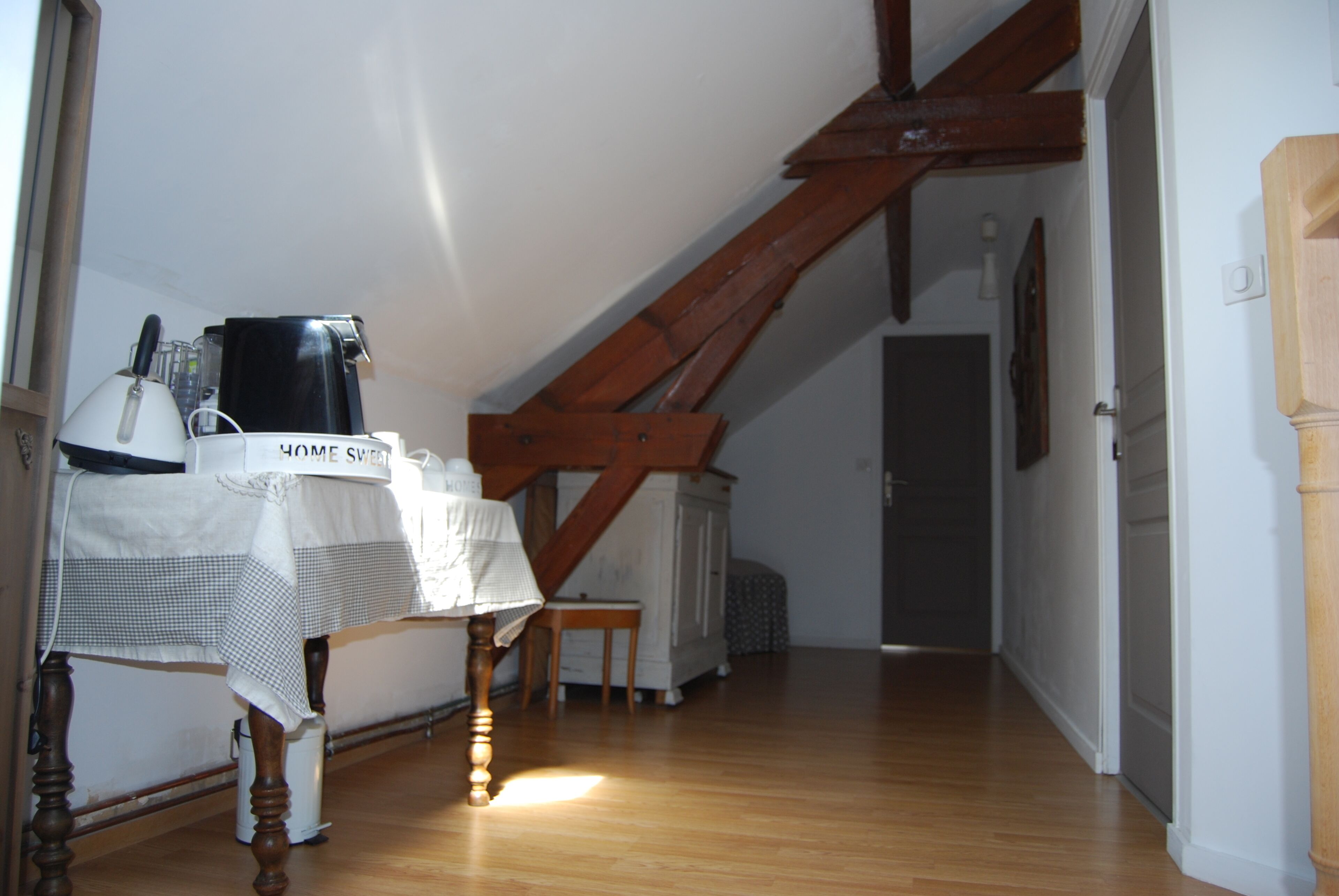 Una habitación con una mesa de madera, una cafetera y un radiador.
