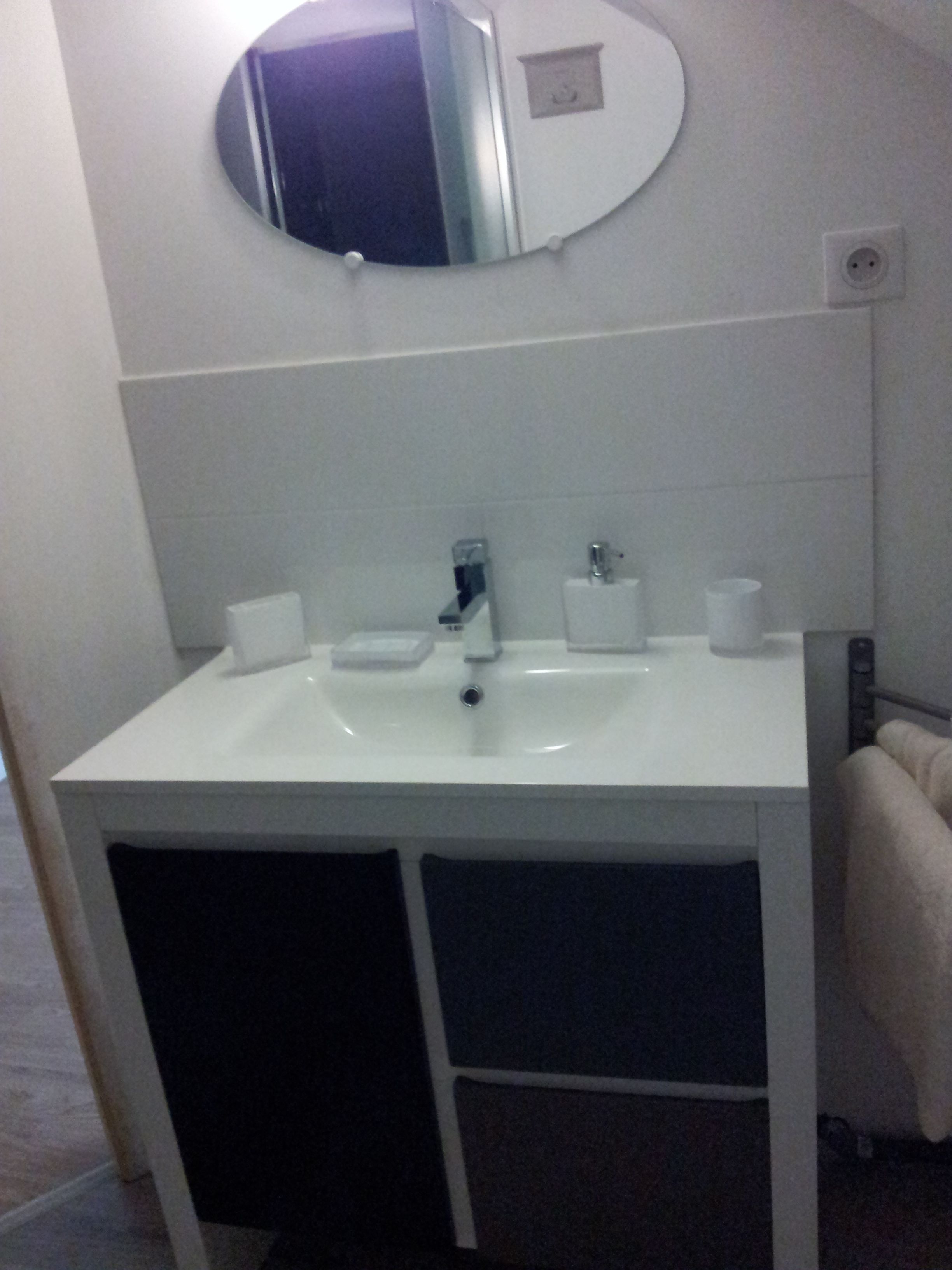 Ein Badezimmer mit einem weißen Waschbecken, einem Spiegel darüber und einem Handtuch an der Wand.