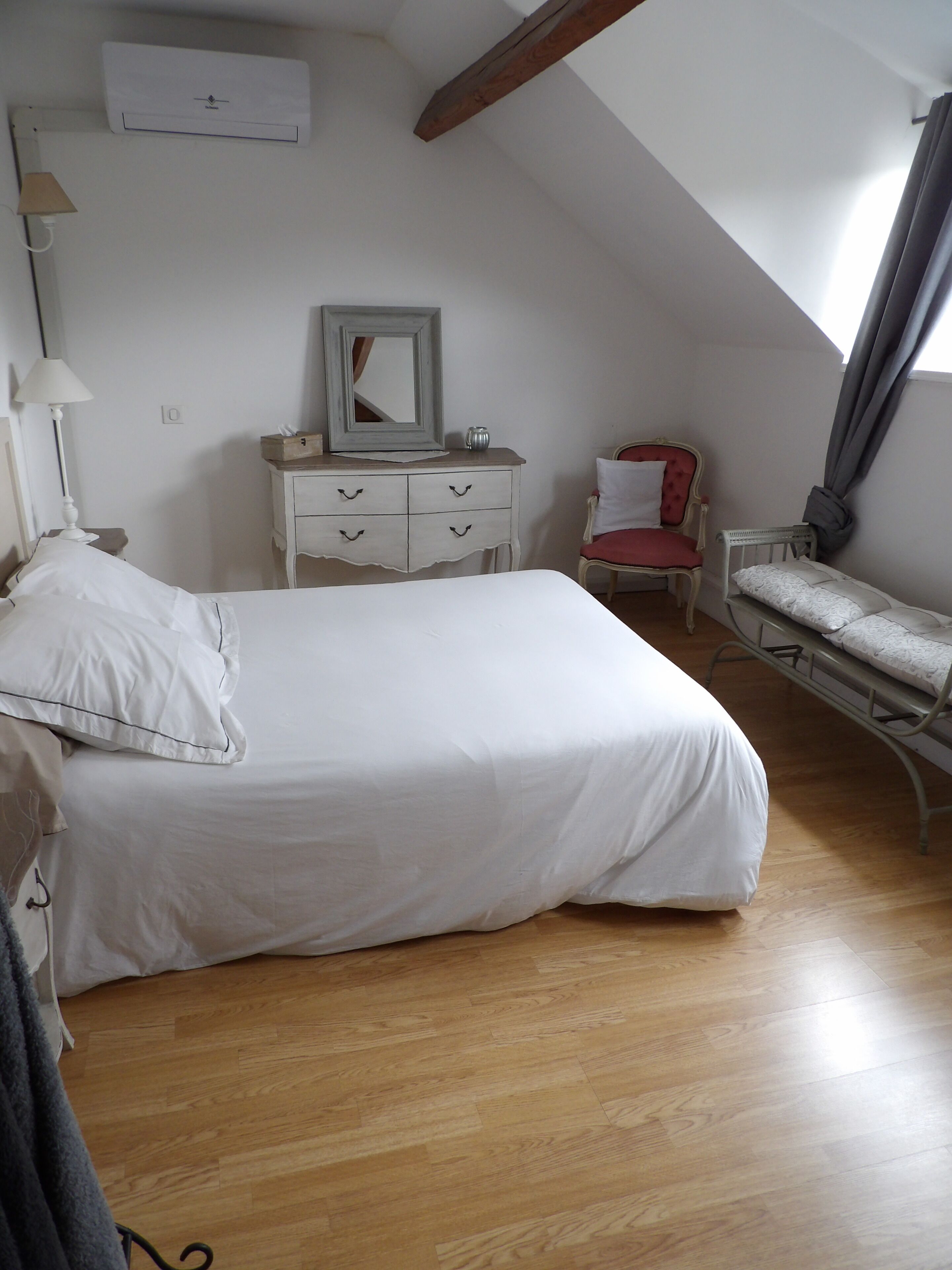A bedroom with a large bed, a dresser, a chair, and a small table.